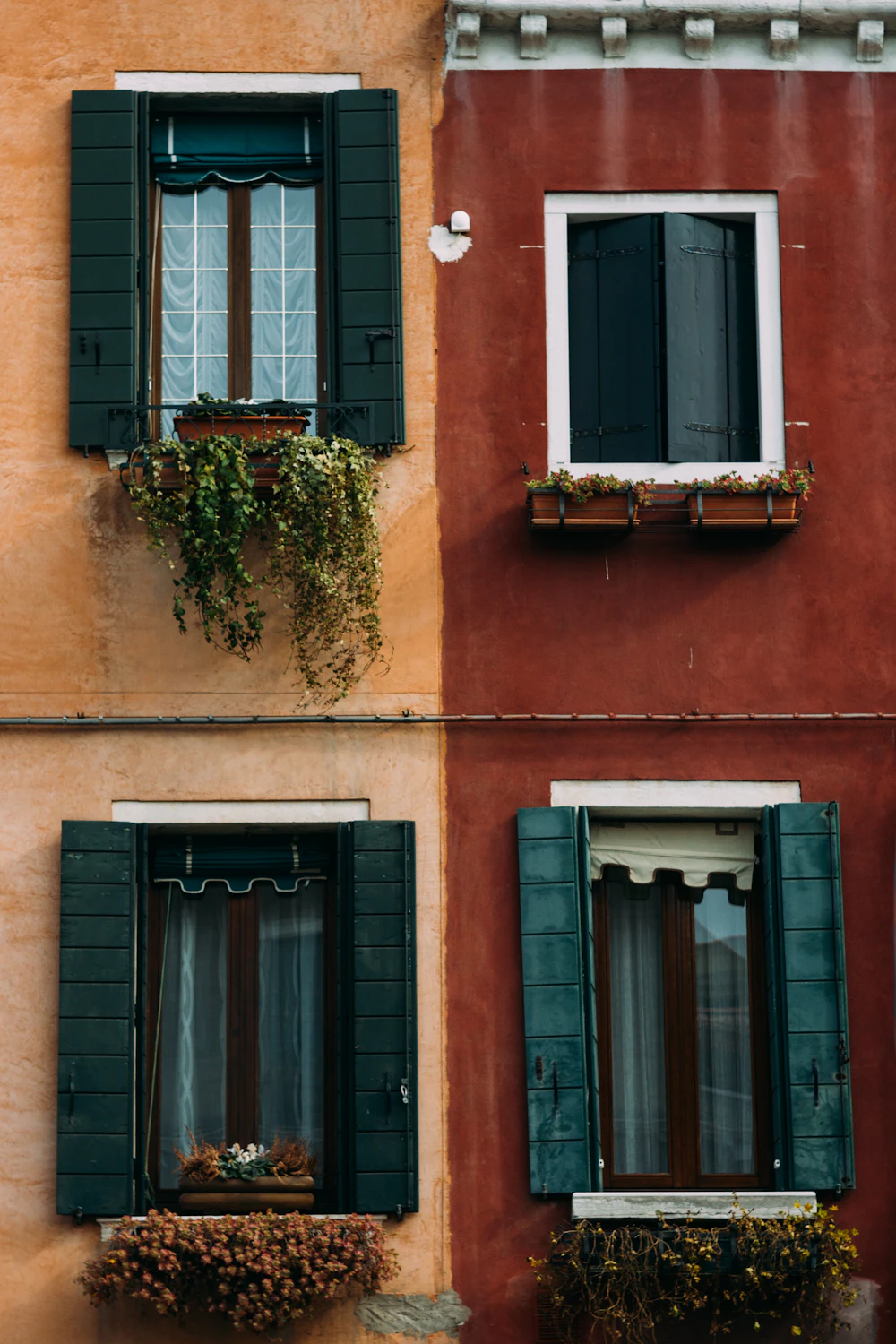 Due facciate affiancate, ocra e rosso, con persiane verdi